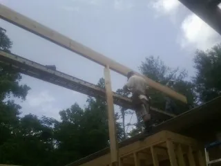 Carpenter setting a ridge beam over a new addition frame — Ice Dam Removal by Roofing Brothers in Springville